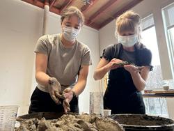 two students working side by side on clay