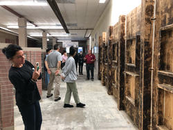 students photograph a stained clay surface inside a warehouse space