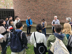 several people gathered outdoors in a courtyard with a large brick exterior in the background