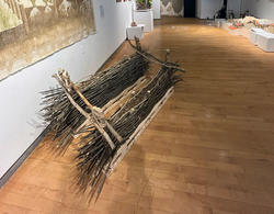 two bundles of uniformly sized sticks lain down on a gallery floor