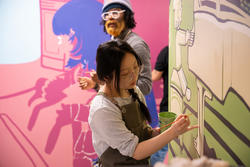 A student paints a wall mural