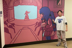 A student smiles next to a mural