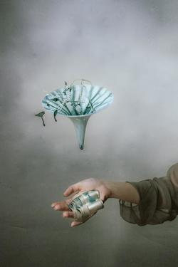 A light blue trumpet shaped floral pieces appears to be floating above an outstretched hand.
