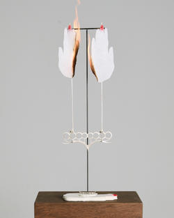 A metal stand holds two hand shaped objects that are on fire.