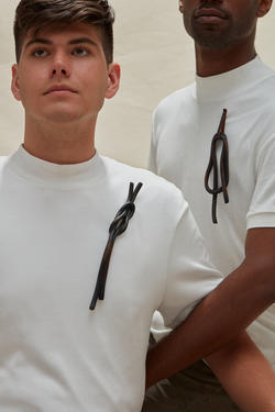 Two people in white shirts are wearing dark metallic broaches.