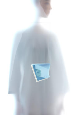 A blue artwork hangs on a square thread with a person draped in white in the background.