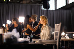 A model getting hair and makeup touched up back stage